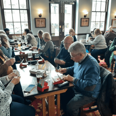 People seated in a cafe around tables playing the card game bridge